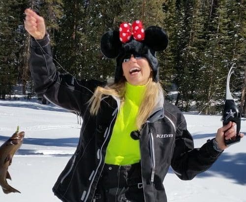 Woman in a wintery scene waving and wearing a Minnie Mouse Knit Cap
