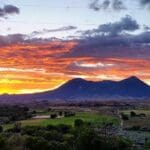 sunset behind a mountain range and green fields
