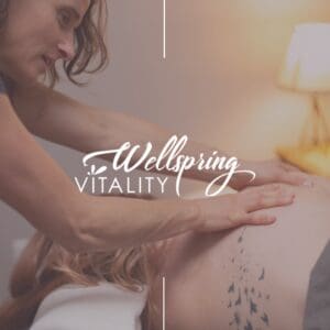 Massage Therapy Session
A close-up, soft-focus image of a massage therapist performing bodywork on a client's back. The client is lying face down with a white towel tucked near their head, revealing a large bird and dandelion silhouette tattoo on their shoulder blade. The "Wellspring Vitality" logo is overlaid in white text in the center of the image.