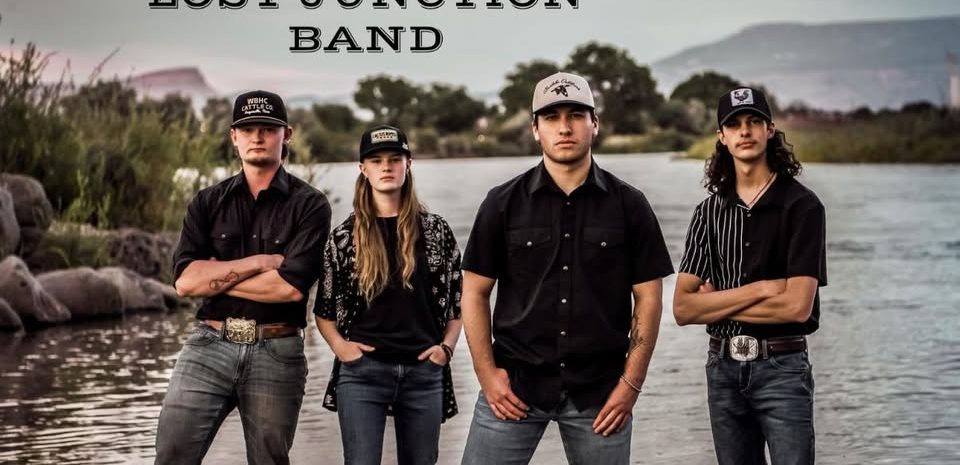 The Lost Junction Band logo and 4 band members standing tin the river