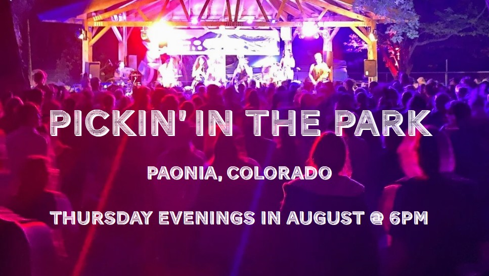 A large crowd at an outdoor night concert in a park. A band performs on a bright purple-lit stage under a wooden pavilion. Text reads: Pickin' in the Park.