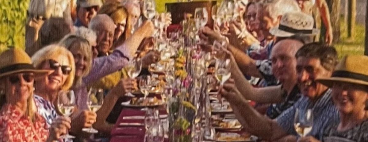 A group of people outdoors at a beautifully set table with wine glasses