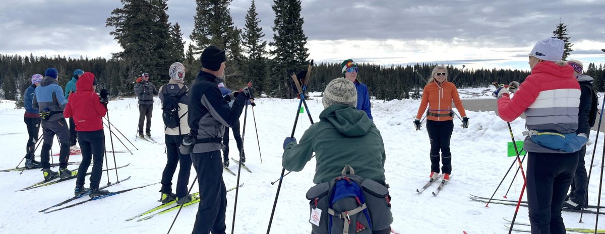 Group of cross-country skiers gathered with poles on snow for an outdoor clinic at Skyway Trailhead on Grand Mesa.