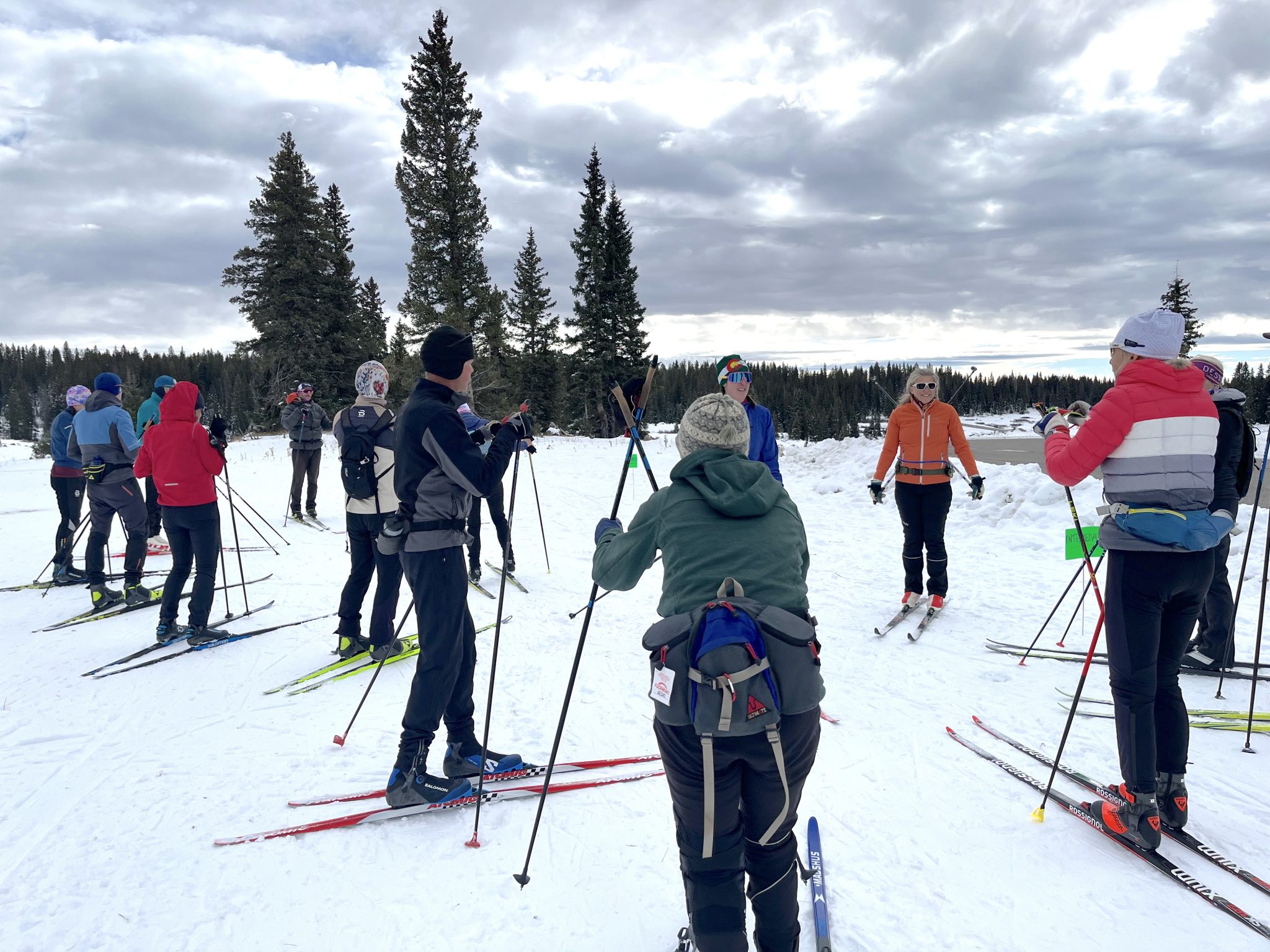 Group of cross-country skiers gathered with poles on snow for an outdoor clinic at Skyway Trailhead on Grand Mesa.
